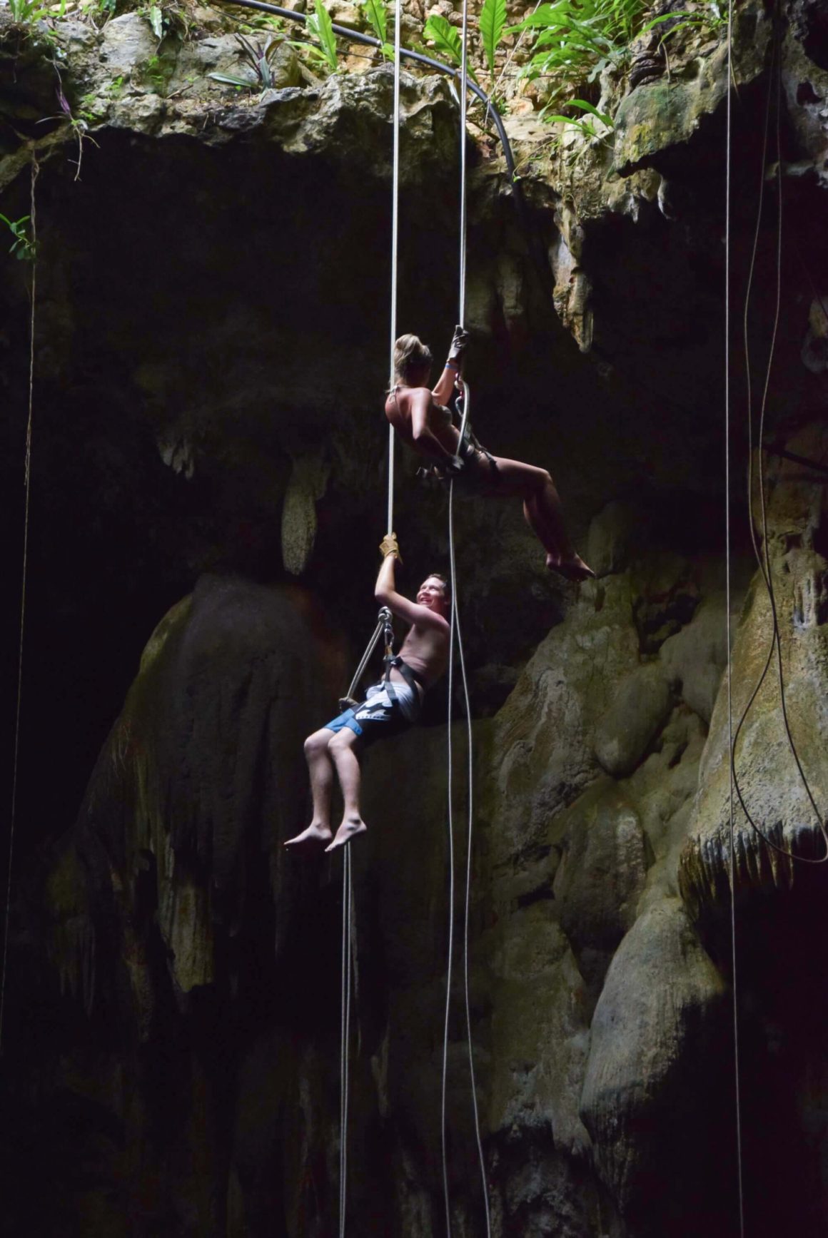 girl and boy (Christina and Jamie) rappelling down into Cenote Maya in Riviera Maya, Mexico